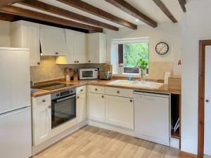 a kitchen with white cabinets and a sink at Grain End in Sawdon