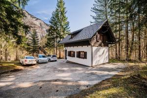 una pequeña casa con coches aparcados en un estacionamiento en Holiday Home Kozorog, en Bohinj