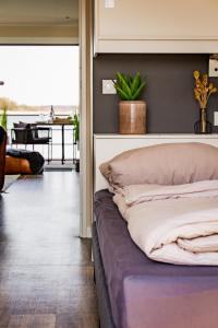 Cama en habitación con vistas a una mesa en Hausboot Küstennebel, en Ribnitz-Damgarten