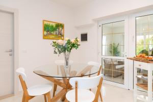 Apartment Meri في سوتيفان: غرفة طعام مع طاولة زجاجية وكراسي بيضاء