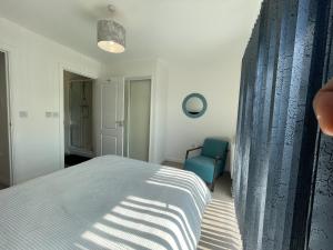 1 dormitorio con 1 cama y 1 silla azul en Stylish Station Apartment in Rochester with Free Parking en Wainscot