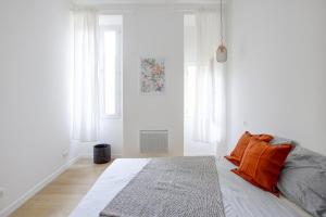 a white bedroom with a bed with orange pillows at Appart Hotel Jaures - Boutique apartments in Nice