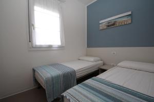 a small room with two beds and a window at Residence Verdena appartamento 03 in Rosolina Mare