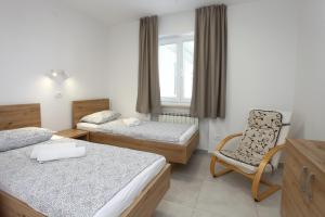 a hotel room with two beds and a chair at Sea View Apartments Portoroz ZM in Portorož