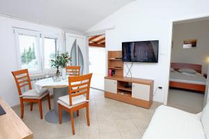 uma sala de estar com uma mesa e cadeiras e uma televisão em Sea View Apartments Portoroz ZM em Portorož