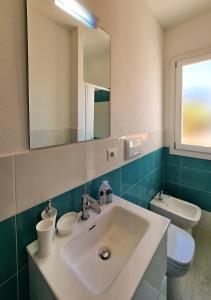 een badkamer met een wastafel, een toilet en een spiegel bij Murphy Holiday Homes - Residenza Solari in La Maddalena