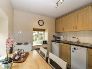 a kitchen with a table and a clock on the wall at Aqueduct Cottage in Abergavenny