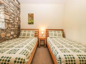 two twin beds in a room with a stone wall at Aqueduct Cottage in Abergavenny