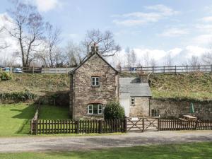 an old stone house with a wooden fence at Aqueduct Cottage in Abergavenny