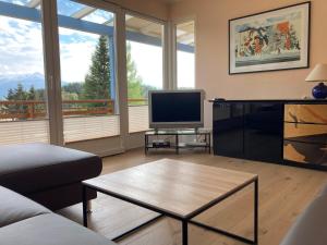 ein Wohnzimmer mit einem Sofa und einem TV in der Unterkunft Ferienhaus Karawankenblick Velden in Velden am Wörthersee