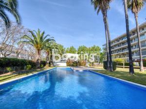 a swimming pool with palm trees and a building at Gavines del Port in Platja d'Aro