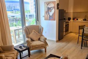 Cowboy Charm 1BR Apartment on Yas Island في أبوظبي: غرفة معيشة مع كرسي ومطبخ