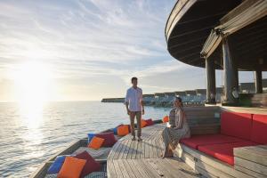 Ein Mann und eine Frau stehen auf einem Boot auf dem Wasser in der Unterkunft Centara Ras Fushi Resort & Spa Maldives in Nord-Malé-Atoll