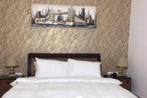 um quarto com uma cama branca, 2 mesas de cabeceira e 2 candeeiros. em Cowboy Charm 1BR Apartment on Yas Island em Abu Dhabi