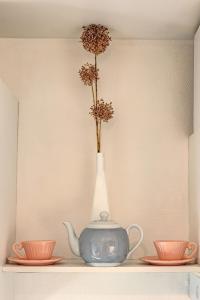 a vase with flowers in it on a shelf with two cups at Appartement la Toscanelle - Quartier historique - Gaillac in Gaillac