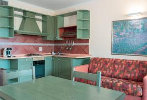 ピアーノ・デッレ・ピエーヴェにあるCarpediem Assisi Living Clubのキッチン(緑のキャビネット、テーブル、ソファ付)
