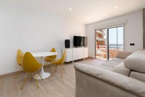 een woonkamer met een bank, een tafel en gele stoelen bij ApartUP La Concha Beachfront II in Oropesa del Mar