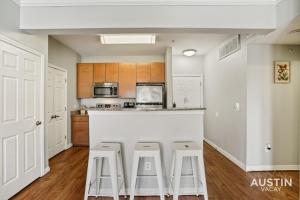 a kitchen with a white counter and stools in it at Extremely Comfortable King Beds in Super Cute Apt in Austin