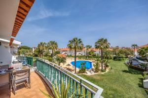 a balcony with a view of a pool and palm trees at Vila Sol with Pool, Garden & Rooftop Terrace in Quarteira