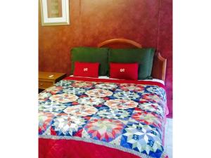 Cama con almohadas rojas y colcha colorida en Grand Inn, en Big Lake