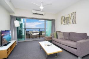 een woonkamer met een bank en een tv bij Pandanas Apt 7 15th fl with harbour and city views in Darwin