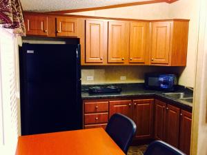 a kitchen with a black refrigerator and wooden cabinets at Grand Inn in Big Lake