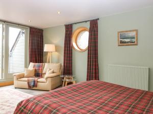 a bedroom with a bed and a chair and a window at Glen Cruick in Kirriemuir