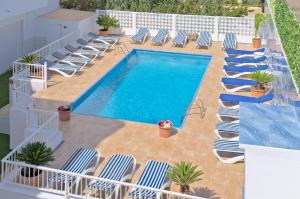 an overhead view of a swimming pool with chaise lounge chairs at All Suite Ibiza Aparthotel in San Antonio