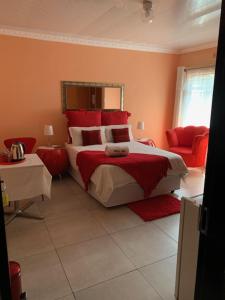 a bedroom with a large bed with red pillows at Sikhula Sonke Guest House in Erasmus