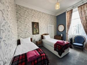 een slaapkamer met 2 bedden en een stoel bij Eliza House in Edinburgh