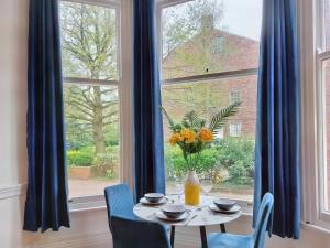 une table avec un vase de fleurs assis devant une fenêtre dans l'établissement The Yorkshire Hosts - Langton Lodge Apt.3, à Wakefield