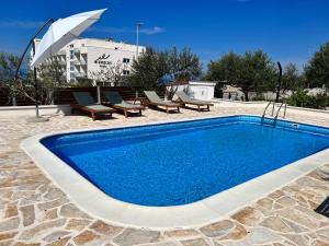 a swimming pool with chairs and an umbrella at Apartments JoDi pool Novalja in Novalja
