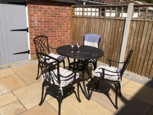 a black table with two chairs and two glasses of wine at Hattie's Cottage in Lincoln