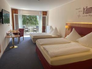 a hotel room with two beds and a table at Hotel Häfner in Bad Schonborn