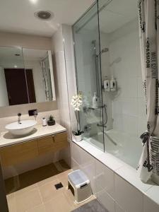 y baño blanco con lavabo y ducha. en Waterfront Escape 2Bdr, Wavepool, Restaurants, en Darwin