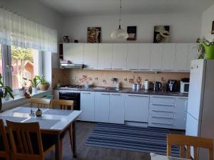 cocina con armarios blancos, mesa y nevera en Ubytování u Solárky, en Trojanovice