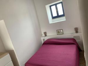 um pequeno quarto com uma cama com um cobertor roxo em Casa Cristian Stromboli em Stromboli