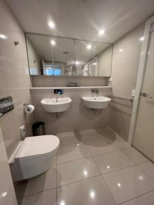a bathroom with two sinks and a toilet and a mirror at Sky high with harbour views in Darwin