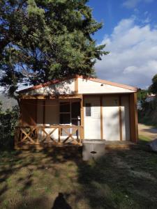 Cabaña pequeña con porche y árbol en Camping TIKITI en Propriano