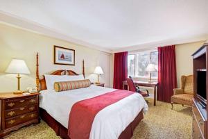 シーコンクにあるRamada by Wyndham Seekonk Providence Areaのベッドとテレビが備わるホテルルームです。