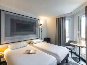 um quarto de hotel com duas camas e uma televisão de ecrã plano em ibis Nancy Centre Stanislas em Nancy