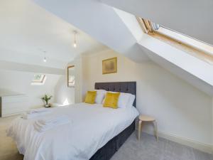 a bedroom with a large white bed with yellow pillows at Duplex Redhill town centre Apt by Livingo Stays in Redhill