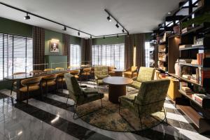 a library with chairs and a table and books at Radisson Collection Hotel, Santa Sofia Milan in Milan