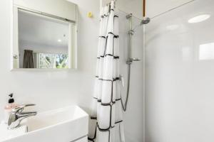 a bathroom with a shower and a sink and a mirror at Torbay 1BR Bolthole - WiFi - Seaviews in Auckland