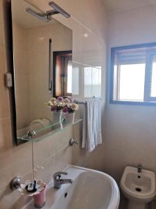 uma casa de banho com um lavatório, um espelho e um WC. em ''O Veleiro'' Rest. Resid. em Torreira