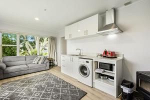 a kitchen and living room with a washer and dryer at Torbay 1BR Bolthole - WiFi - Seaviews in Auckland