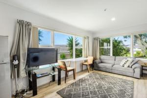 a living room with a couch and a tv at Torbay 1BR Bolthole - WiFi - Seaviews in Auckland