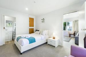 a white bedroom with a bed and a mirror at Torbay 1BR Bolthole - WiFi - Seaviews in Auckland