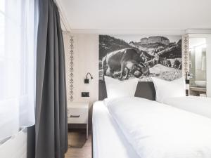 a bedroom with two beds and a painting on the wall at Traube Restaurant & Hotel in Appenzell