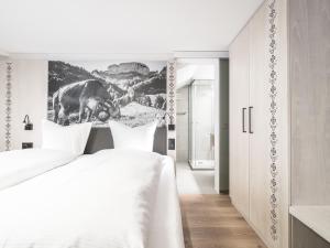 a white bedroom with a cow picture on the wall at Traube Restaurant & Hotel in Appenzell